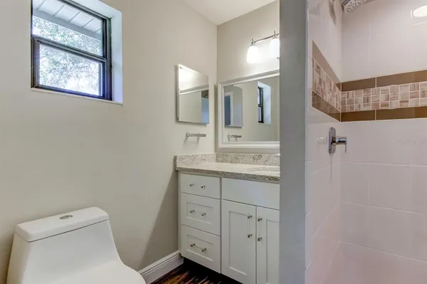 a bathroom with a granite countertop toilet sink and mirror