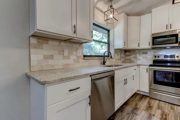 a kitchen with stainless steel appliances granite countertop a sink dishwasher a stove and a microwave oven with cabinets