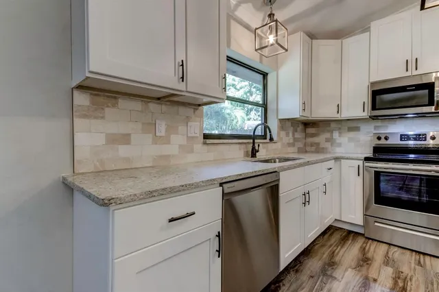 a kitchen with stainless steel appliances granite countertop a sink dishwasher a stove and a microwave oven with cabinets