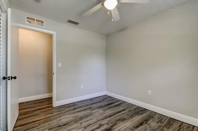 an empty room with wooden floor cabinet and windows