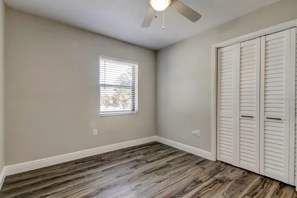 an empty room with wooden floor cabinet and windows