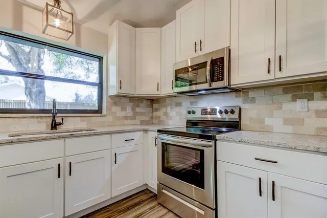 a kitchen with stainless steel appliances granite countertop white cabinets a sink and a stove