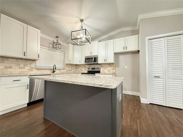 a kitchen with stainless steel appliances granite countertop a sink a stove a refrigerator cabinets and wooden floor