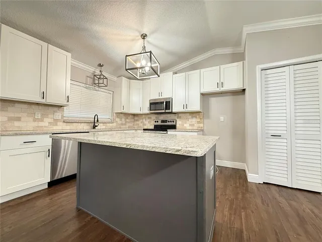 a kitchen with stainless steel appliances granite countertop a sink a stove a refrigerator cabinets and wooden floor
