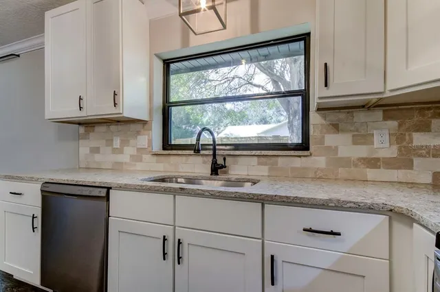a kitchen with granite countertop white cabinets and a window