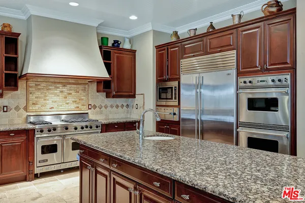 a kitchen with stainless steel appliances kitchen island granite countertop a stove refrigerator and microwave