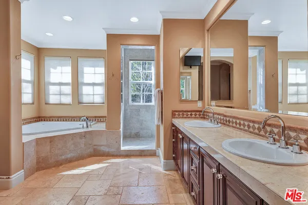 a large bathroom with a granite countertop sink a mirror a bathtub and next to a window