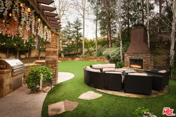 a view of a backyard with couches table and chairs and potted plants