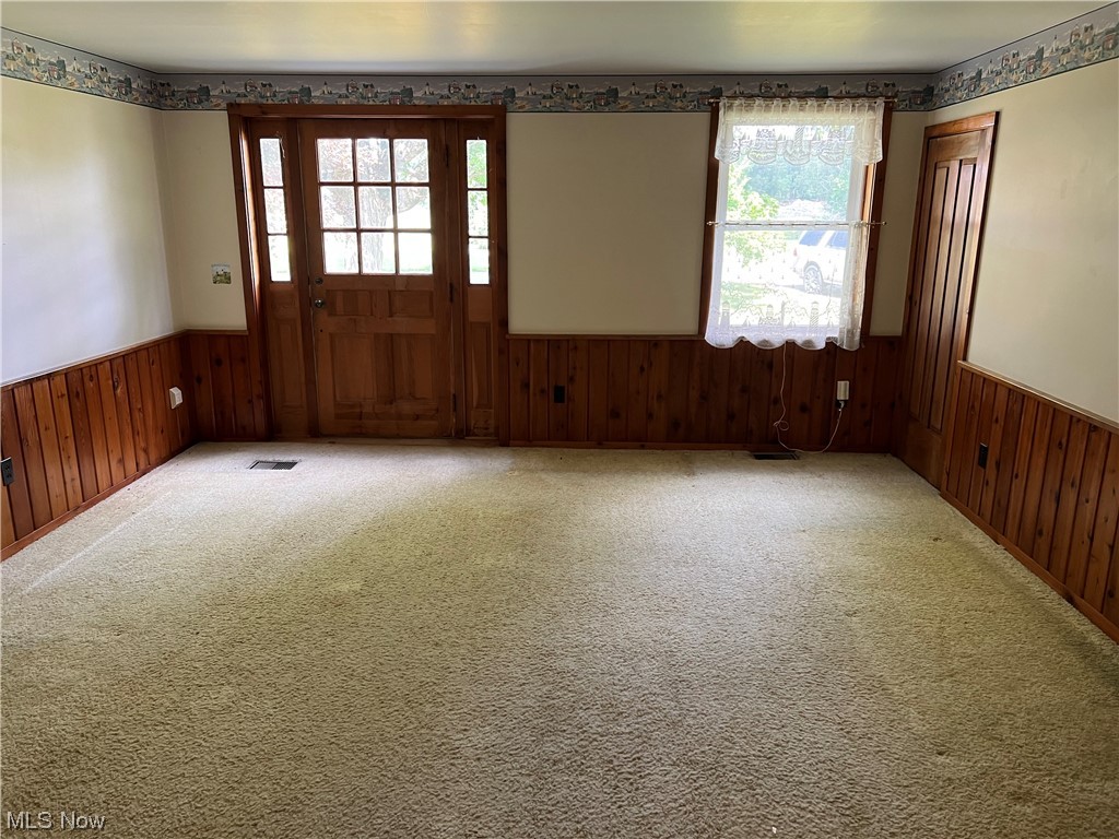 11178 Simcox Road Homerville, OH 44235 - Photo 8 of 17 Carpeted empty room with a wealth of natural light and wood walls