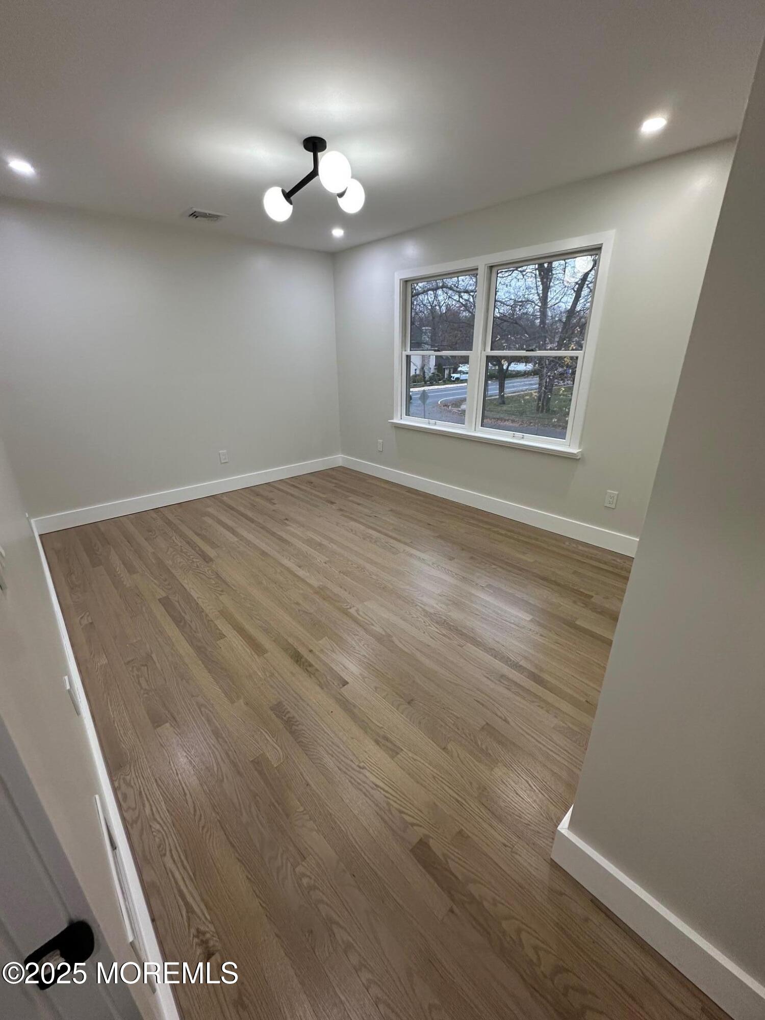 469 Wall Street Eatontown, NJ 07724 - Photo 12 of 17 an empty room with wooden floor chandelier and windows
