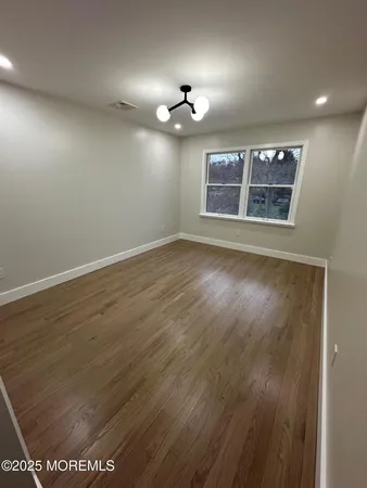 an empty room with wooden floor ceiling fan and window