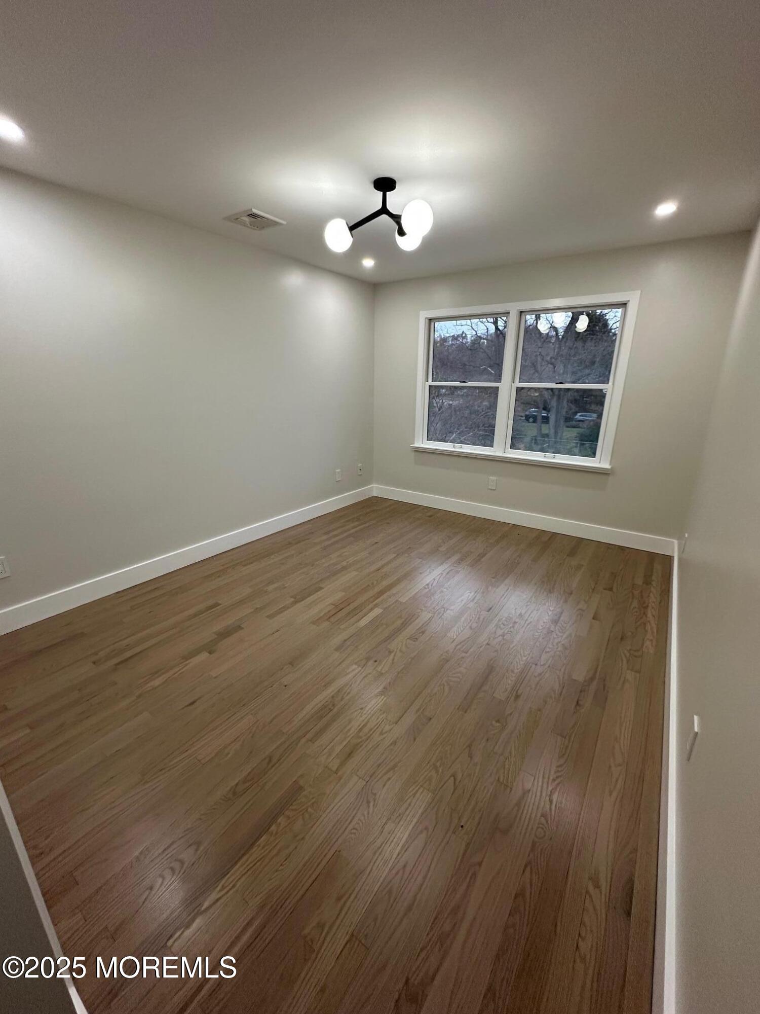 469 Wall Street Eatontown, NJ 07724 - Photo 14 of 17 an empty room with wooden floor ceiling fan and window