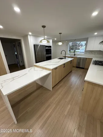 a large white kitchen with sink a refrigerator and a stove