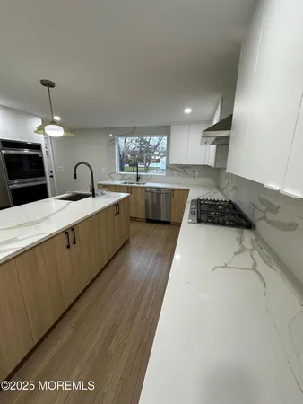 a kitchen with stainless steel appliances granite countertop a sink a stove top oven a counter space and cabinets