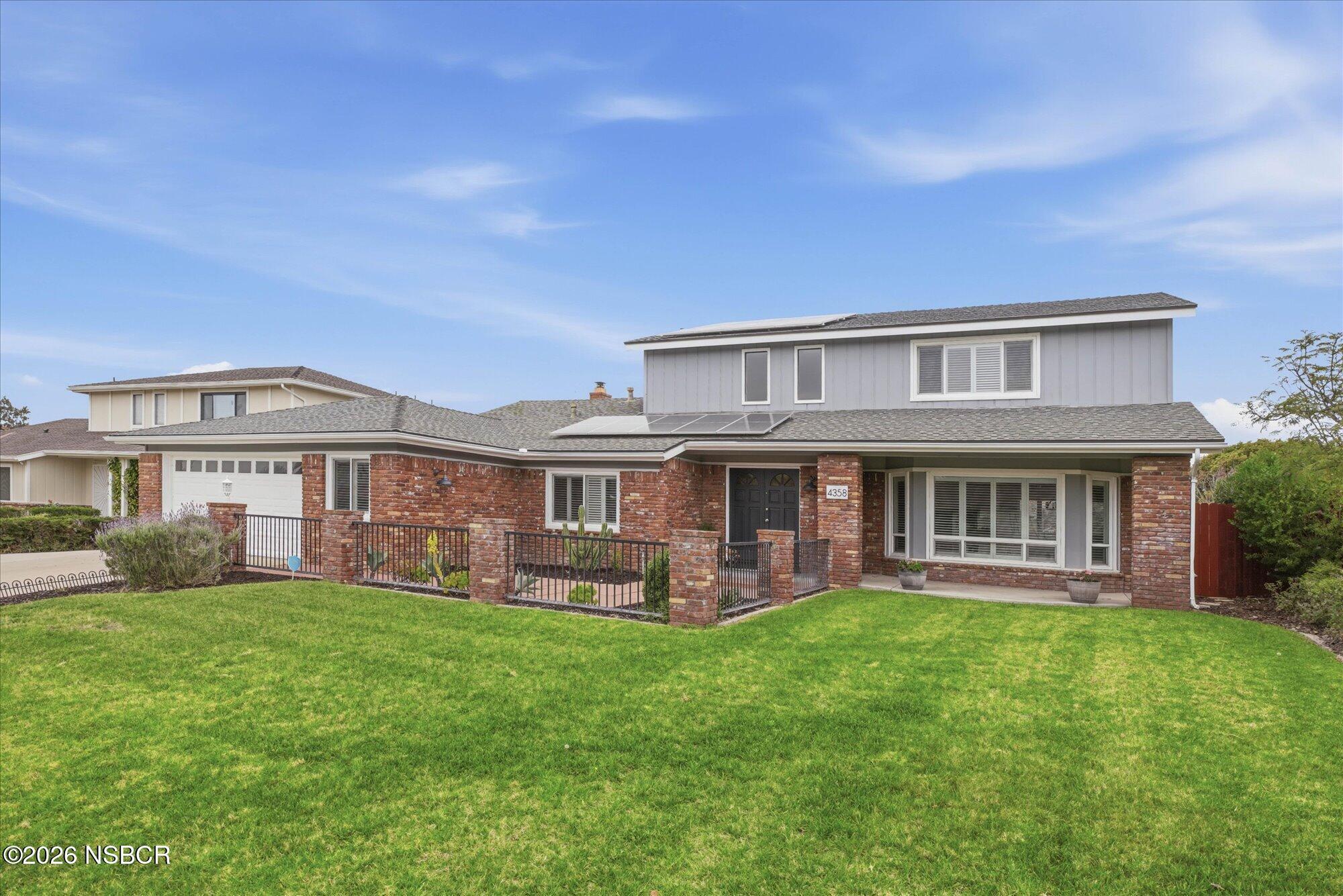 a front view of a house with a yard and trees