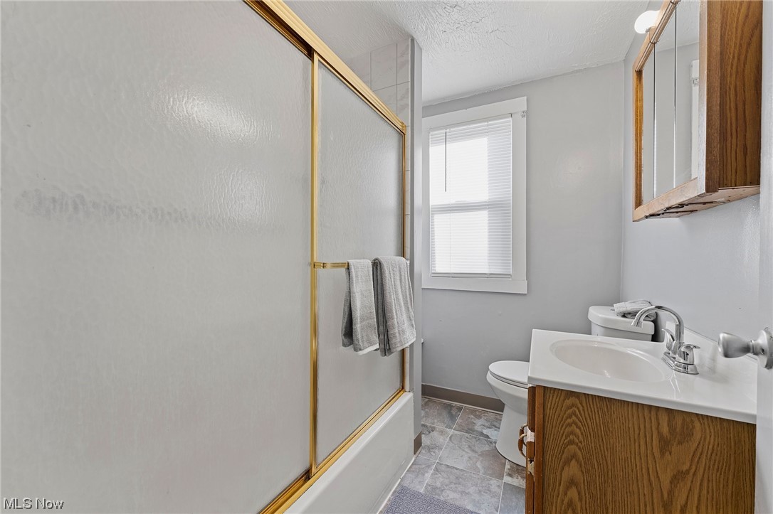 6343 Jefferson Road Ashtabula, OH 44004 - Photo 23 of 31 Full bathroom featuring shower / bath combination with glass door, a textured ceiling, oversized vanity, toilet, and tile flooring