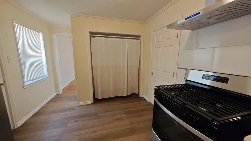 12225 Schroeder Road Dallas, TX 75243 - Photo 11 of 40 Wood-finish flooring, white trim, stainless steel range hood, white subway tile backsplash, and a gas range