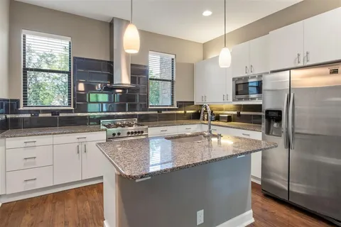 a kitchen with stainless steel appliances granite countertop a sink a stove and a refrigerator