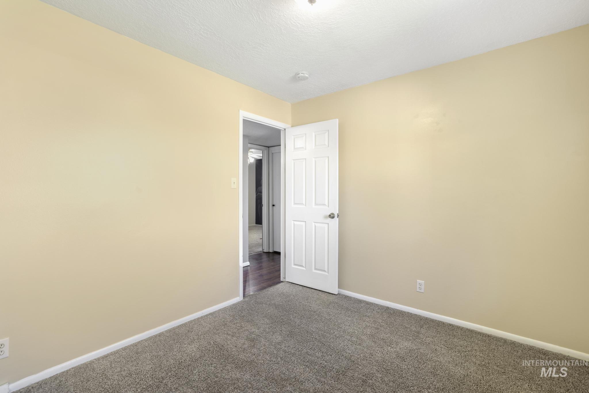 712 Locust Street Kimberly, ID 83341 - Photo 16 of 26 Warm-toned interior room featuring a double-pane window with blinds, light-colored walls, and gray textured carpeting