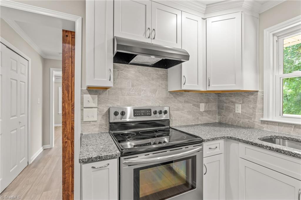 5902 Siler Road Greensboro, NC 27406 - Photo 10 of 49 Electric range with vented exhaust hood. Laundry/mud room is between the kitchen and primary suite.