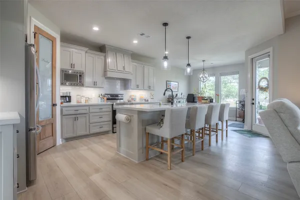 a kitchen with a dining table chairs wooden floor cabinets and stainless steel appliances