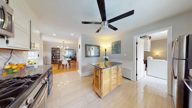 a kitchen with stainless steel appliances kitchen island granite countertop a refrigerator and a stove top oven