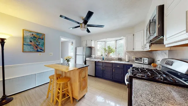 a kitchen with stainless steel appliances granite countertop a stove top oven a sink a dining table and chairs with wooden floor