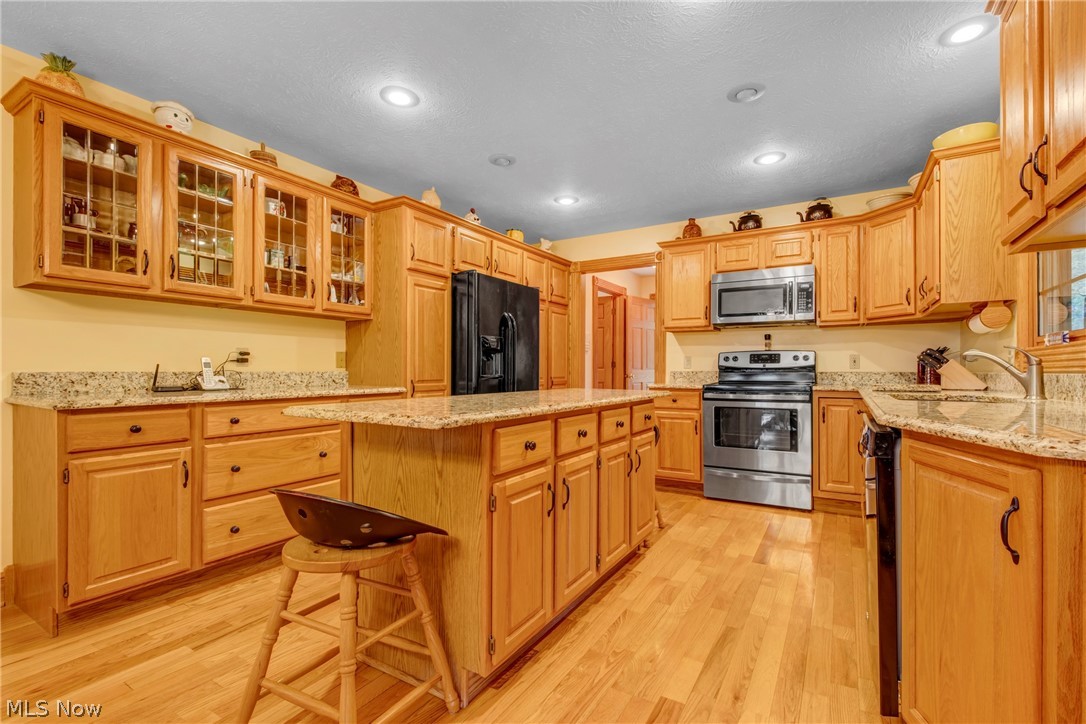 2645 Frost Road Mantua, OH 44255 - Photo 12 of 35 Kitchen featuring a center island, granite countertops, light hard wood flooring, and black appliancesuble pantry