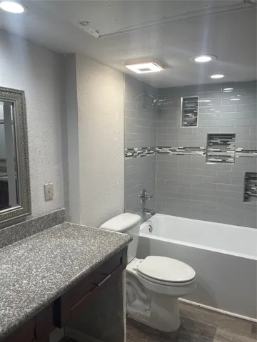 a bathroom with a granite countertop toilet a sink and bathtub
