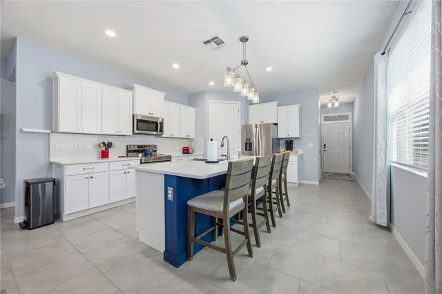 a kitchen that has a lot of white cabinets a sink dishwasher and a refrigerator with wooden floor