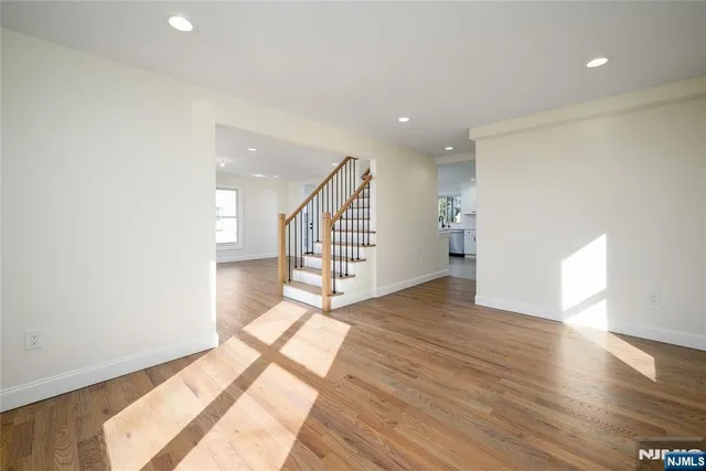 a view of an empty room with wooden floor and stairs