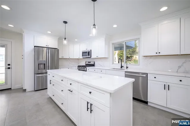 a kitchen with kitchen island white cabinets and stainless steel appliances