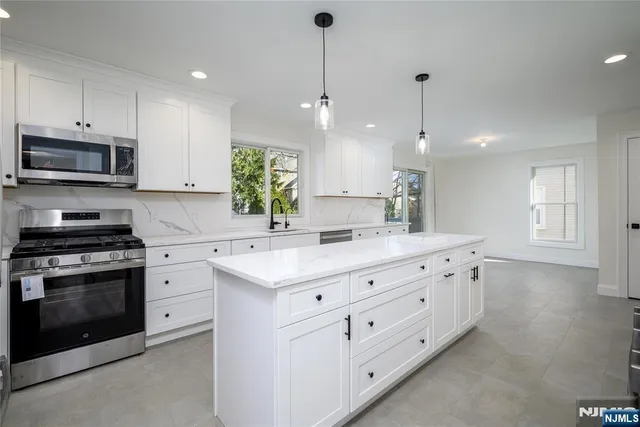 a kitchen with granite countertop white cabinets white stainless steel appliances with a sink and dishwasher