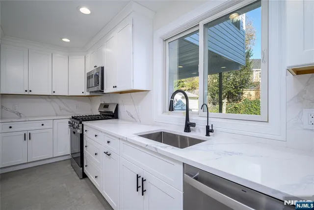 a kitchen with stainless steel appliances granite countertop a sink a stove and a refrigerator