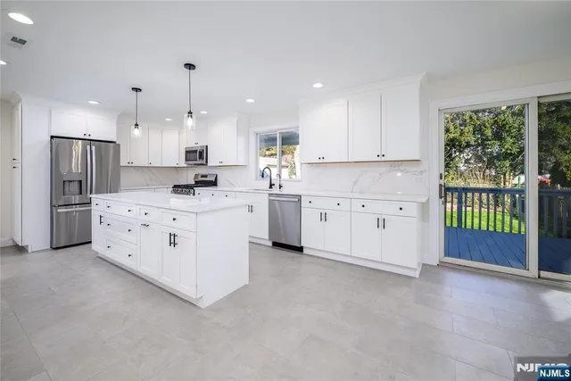 a large white kitchen with a stove a sink a refrigerator a window and a kitchen island