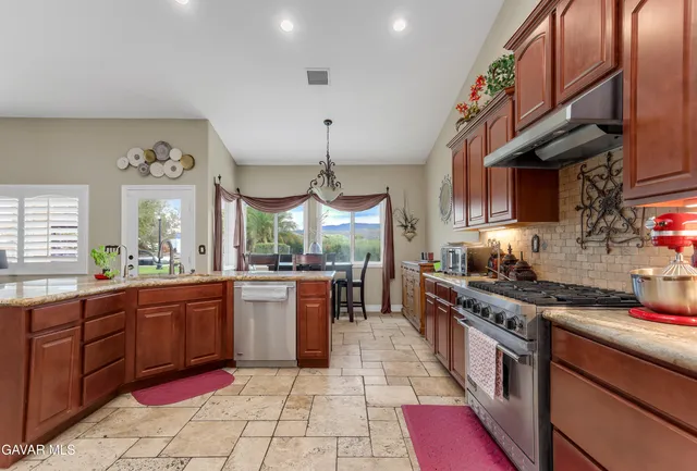 a kitchen with stainless steel appliances granite countertop a stove a sink and a microwave