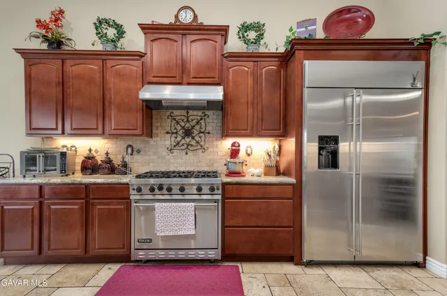 a kitchen with granite countertop a refrigerator stove and cabinets