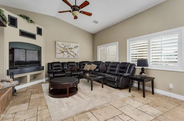 a living room with furniture a flat screen tv and a window