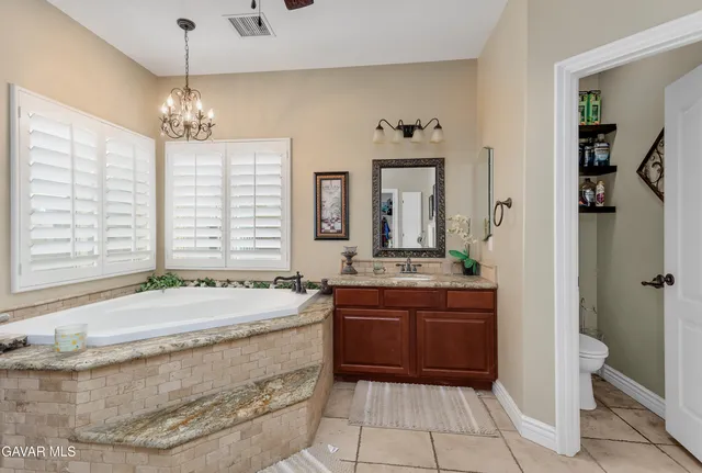 a spacious bathroom with a granite countertop sink a mirror and a bathtub