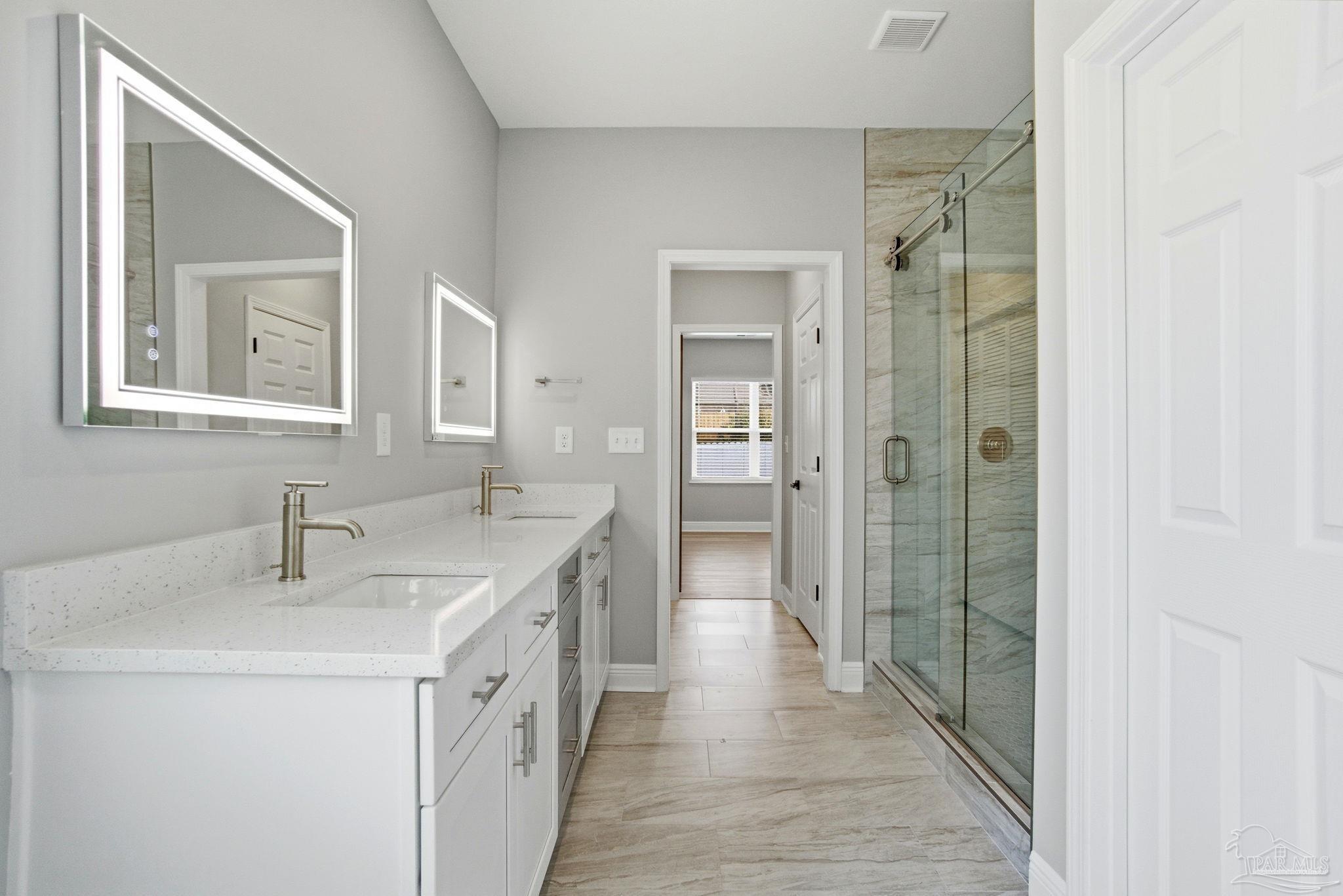 5712 Riviera Drive Milton, FL 32583 - Photo 27 of 41 a spacious bathroom with a double vanity sink a mirror and a shower