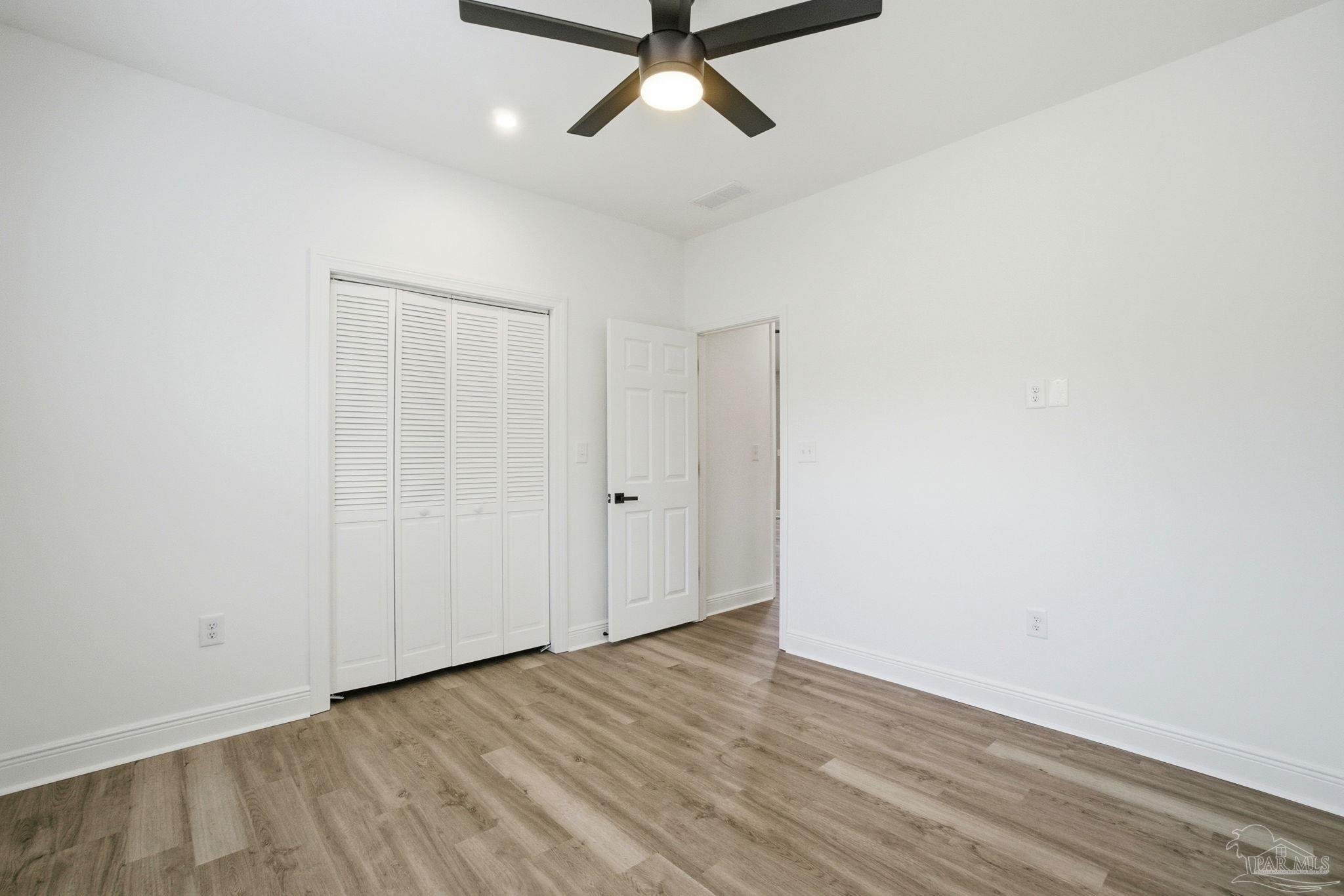 5712 Riviera Drive Milton, FL 32583 - Photo 32 of 41 a view of a room with wooden floor and a ceiling fan