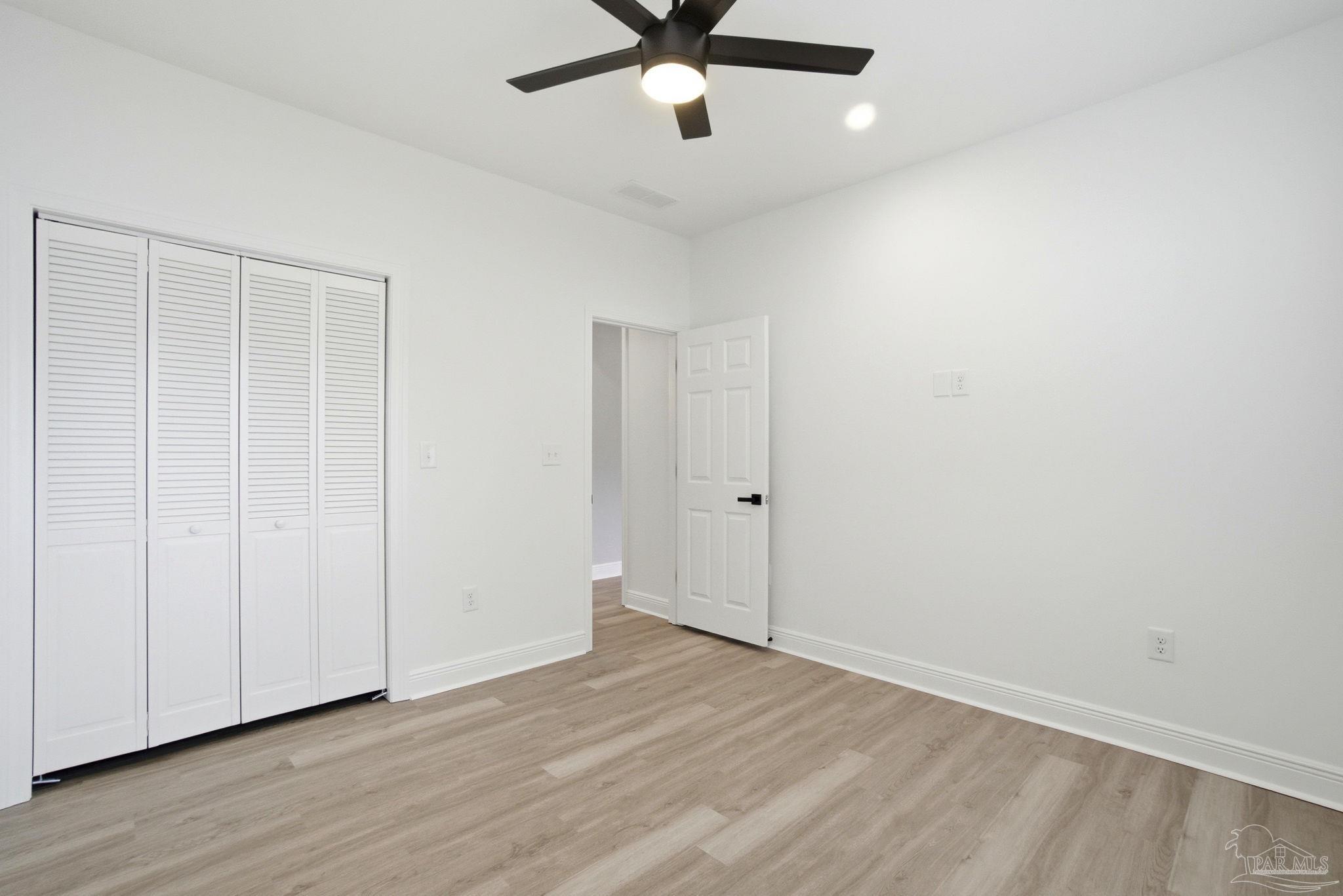 5712 Riviera Drive Milton, FL 32583 - Photo 35 of 41 an empty room with wooden floor ceiling fan and windows