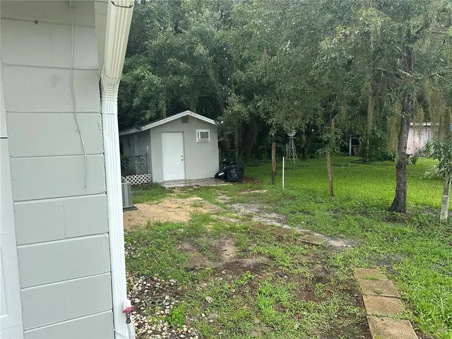 a view of a wooden house with a big yard and large trees