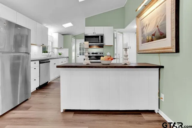 a kitchen with stainless steel appliances a sink a microwave a refrigerator and cabinets