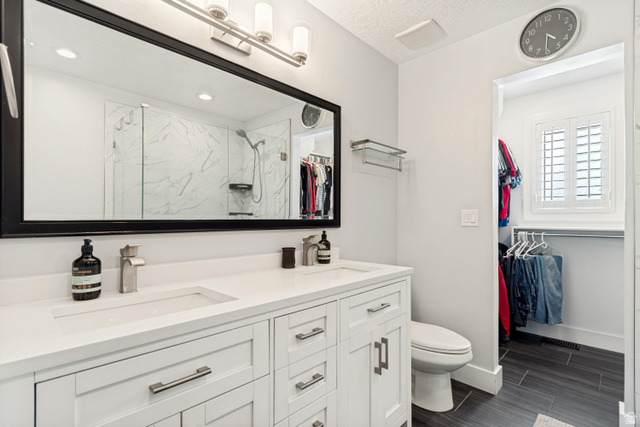 9832 Falconhurst Drive Sandy, UT 84092 - Photo 13 of 29 Double vanity with integrated sinks and brushed nickel faucets, featuring white shaker-style cabinetry and a large framed mirror