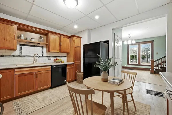 a kitchen with stainless steel appliances granite countertop wooden cabinets a sink a stove a refrigerator with grey cabinets and wooden floor