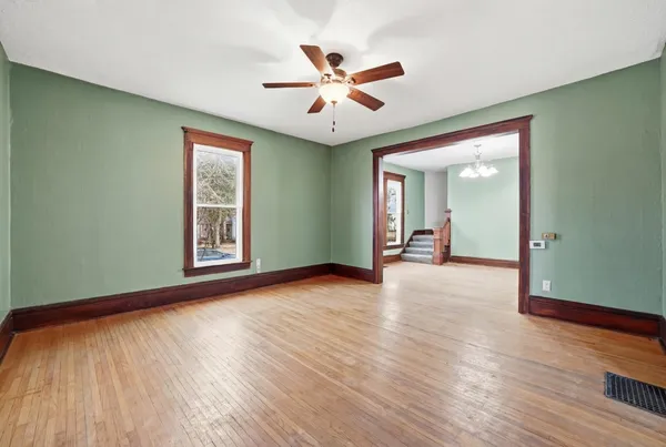 a view of an empty room with wooden floor and a window