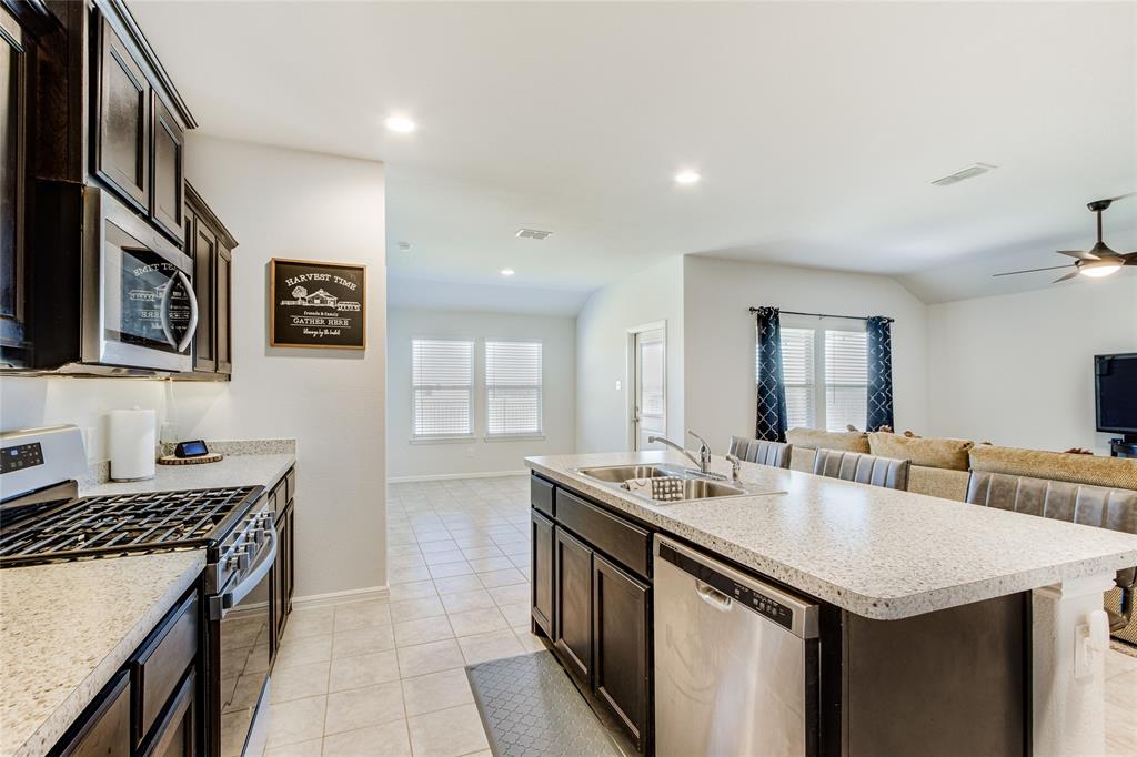 16516 Portage Street Justin, TX 76247 - Photo 11 of 29 a kitchen with stainless steel appliances granite countertop a sink a stove and a refrigerator
