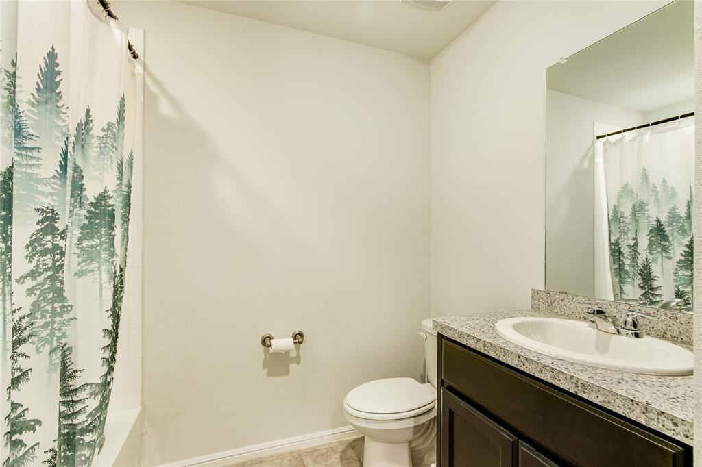 16516 Portage Street Justin, TX 76247 - Photo 22 of 29 a bathroom with a granite countertop sink a toilet and a mirror