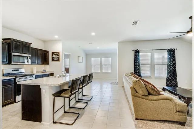 a large white kitchen with stainless steel appliances granite countertop a sink a stove and a refrigerator